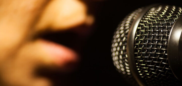 Close up image of a woman singing to a microphone.