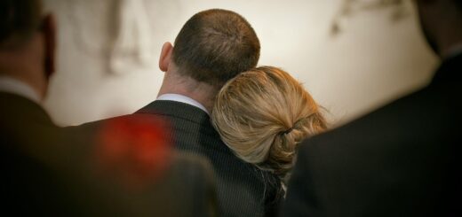 Trauernde Angehörige bei einer Beerdigung – eine Frau sucht Trost, indem sie ihren Kopf an die Schulter eines Mannes lehnt.